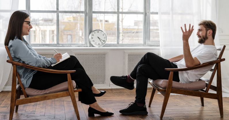 Counseling - Person in Black Pants and Black Shoes Sitting on Brown Wooden Chair