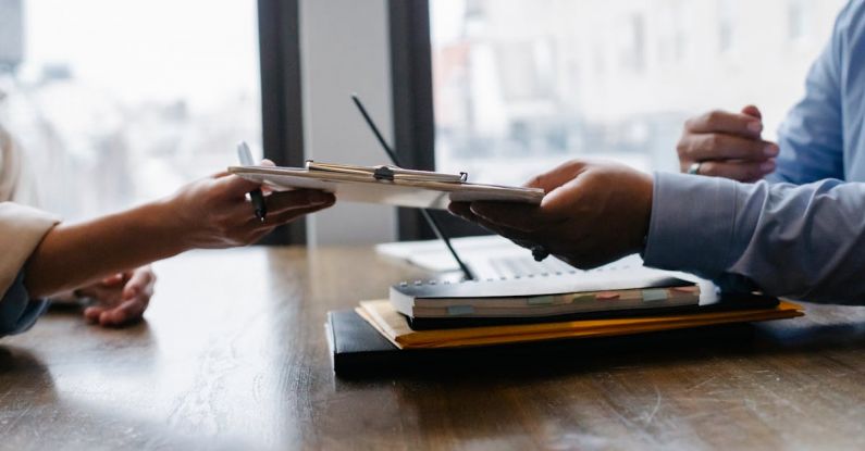 Curriculum - Crop anonymous ethnic woman passing clipboard to office worker with laptop during job interview