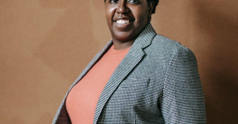 Classroom Management - Smiling adult African American professor in jacket and with dreadlocks smiling at camera