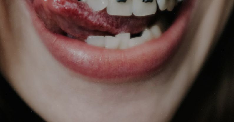 Positive Reinforcement - Crop female with metal braces on upper teeth and nose piercing smiling coquettishly and showing tongue