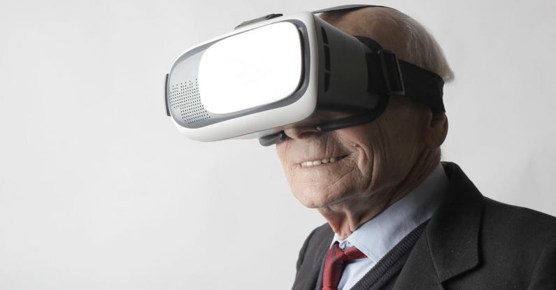 Interactive Whiteboards - Smiling elderly gentleman wearing classy suit experiencing virtual reality while using modern headset on white background