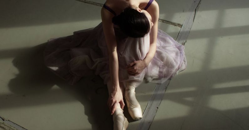 Training - Unrecognizable graceful ballet dancer resting on floor